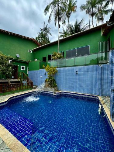 a large swimming pool in front of a green building at Pousada Platôdasilhas in Angra dos Reis