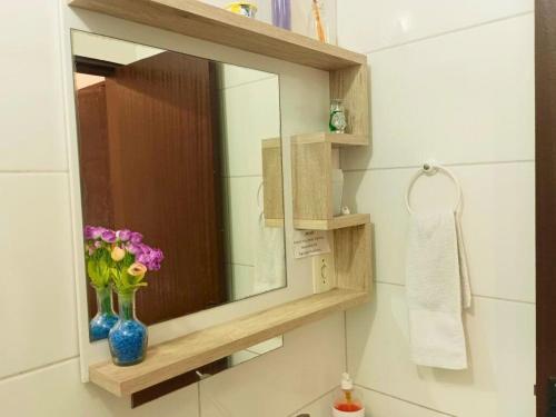 a bathroom with a mirror and a vase with flowers at Pousada Executiva SolRiso Aeroporto Florianópolis in Florianópolis
