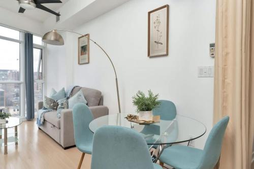 a living room with a glass table and blue chairs at Sunny Downtown TO Studio - Sleeps 3 with 55 TV in Toronto