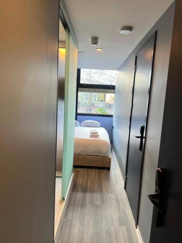 a small bedroom with a bed and a window at The Hyve Budget Hotel Rotterdam in Rotterdam