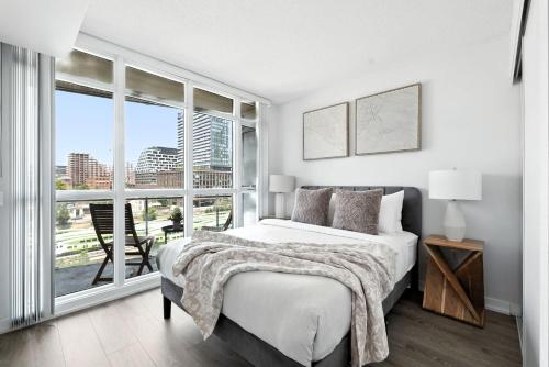 een witte slaapkamer met een bed en een groot raam bij Bright 2BR Condo with by the Waterfront in Toronto