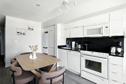 een keuken met witte kasten en een tafel met stoelen bij Bright 2BR Condo with by the Waterfront in Toronto