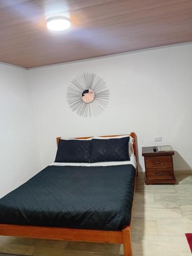 a bedroom with a bed and a clock on the wall at Casa Alto de la Virgen DeMaiz in Choachí