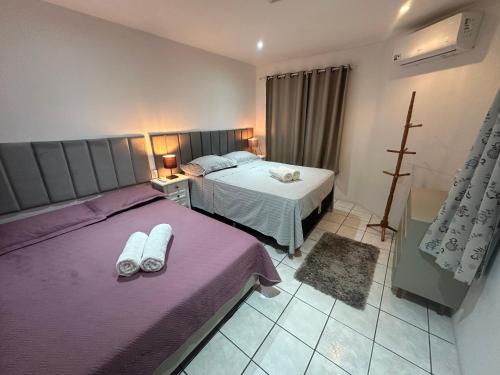 two beds in a bedroom with purple sheets at Beira Mar Continental (mágica!) in Florianópolis