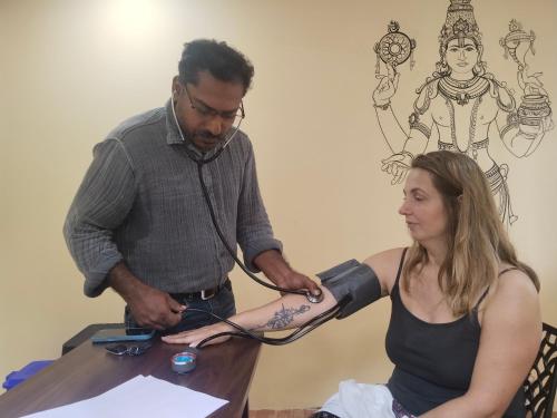 a man getting a tattoo on the arm of a woman at iha ayurveda resort in Varkala