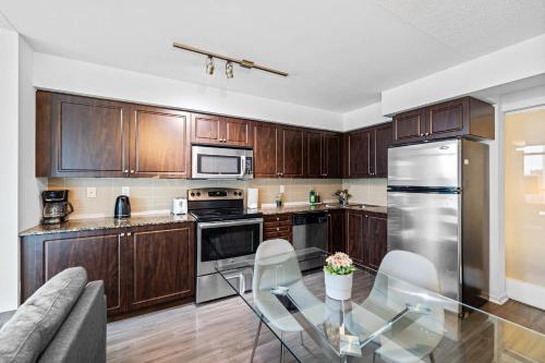 een keuken met houten kasten en een glazen tafel bij Spacious 3BR Condo with Patio & Free Parking in Toronto