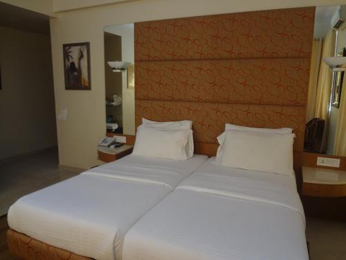 a bedroom with a large bed with white sheets at Astoria Hotel in Mumbai