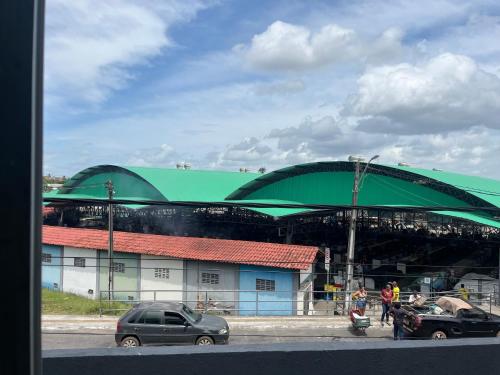 a large green building with cars parked in a parking lot at Pousada Sossego in Pojuca