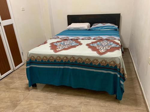 FELIZ ESTADIA Via PRINCIPAL PUERTO LOPEZ في بويرتو لوبيز: سرير عليه بطانية زرقاء وبنية اللون