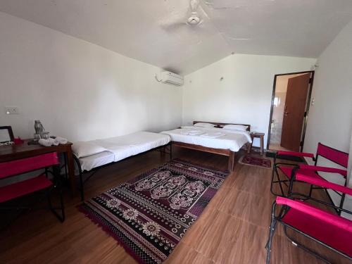 a room with two beds and a table and chairs at Home in the Jungle in Seonī