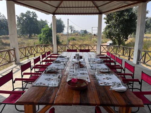 a long wooden table with chairs and plates on it at Home in the Jungle in Seonī