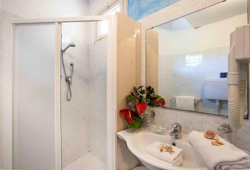 a white bathroom with a shower and a sink at Hotel Calypso in Cesenatico