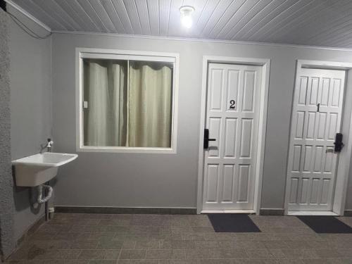 een badkamer met een wastafel en een spiegel en 2 deuren bij Studios Cordeiros in Itajaí