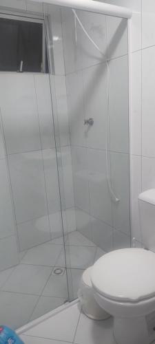 Un baño blanco con ducha y WC. en Suíte na rua da praia, en Porto Belo