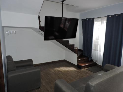 een woonkamer met een bank en een tv aan de muur bij Silver Mountain House in Taxco de Alarcón