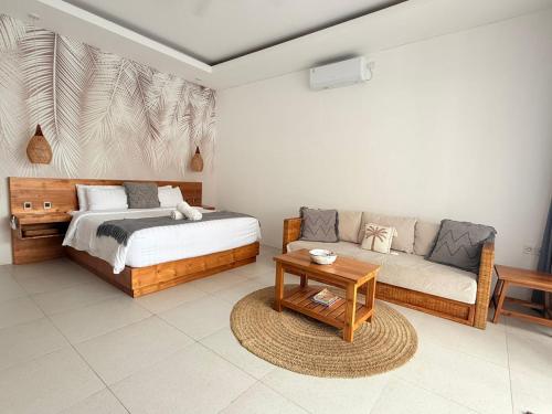 a bedroom with a bed and a couch and a table at Santai Suites Nusa Dua in Nusa Dua