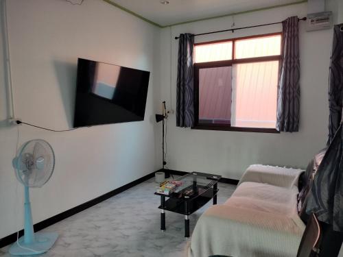 a living room with a couch and a tv on the wall at Soi Saliga in Rawai Beach