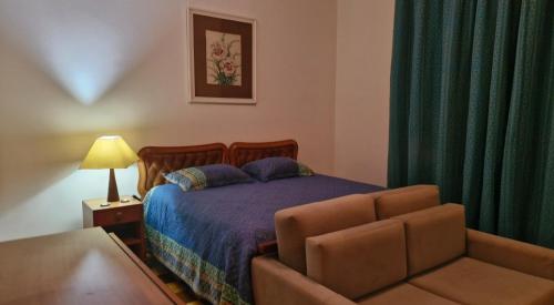 een slaapkamer met een bed en een bank bij Suite Palácio Quitandinha in Petrópolis