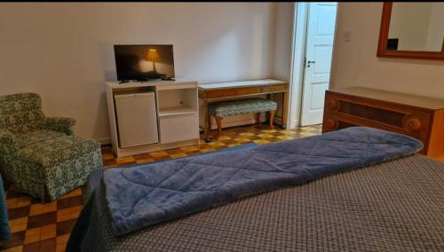 een slaapkamer met een bed, een tv en een stoel bij Suite Palácio Quitandinha in Petrópolis