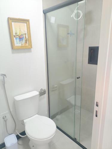 a bathroom with a toilet and a glass shower at Studio Borboletas de luz in Bombinhas