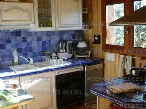 Una cocina con azulejos azules en las encimeras y una estufa. en Chalet indépendant confortable pour 6, proche pistes - FR-1-295-212, en Les Angles