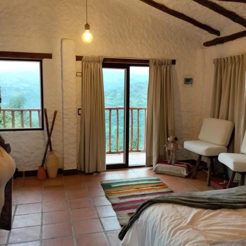 a bedroom with a bed and a balcony with windows at Posada Iglesia Vieja in Soatá