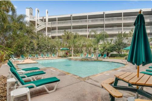 a pool with chairs and umbrellas in front of a building at Galveston condo- walk to beach - ocean view - 2 pools in Galveston