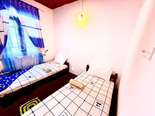 two beds in a small room with a window at DILSHAN HOTEL Diyaluma in Koslanda