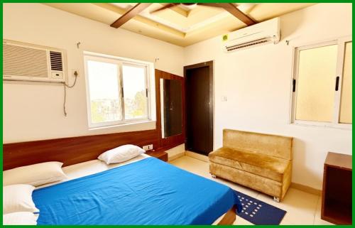 a bedroom with a blue bed and a chair at Mahakaleshwar jyotilinga Temple Dwarika - Dhish Premium near Railway station, Fully Air conditioned Rooms -wifi- Lift and Restaurant Facilities, BEST HOTEL IN UJJAIN in Ujjain