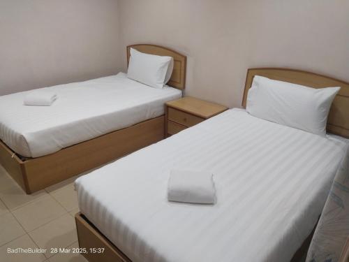 Zwei Betten in einem kleinen Zimmer mit weißen Laken in der Unterkunft BBHotel in Gerik