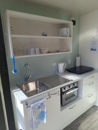 a small kitchen with a sink and a counter top at Riverview Studio in Te Puru