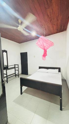 a room with a bed with a pink umbrella at chula,s Home Stay in Matara