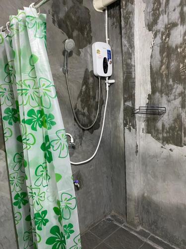 a shower in a bathroom with a shower curtain with a shower at Phunara Guest House in Phatthalung