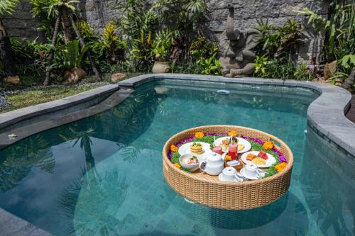een mand gevuld met voedsel in een zwembad bij The Runik Ubud in Ubud