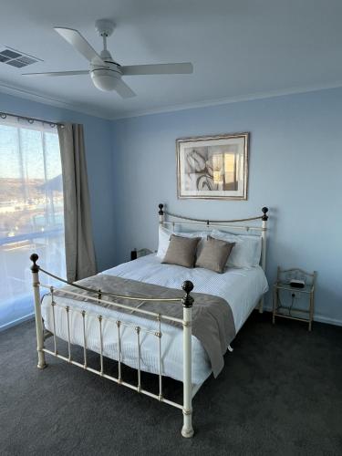 a bedroom with a white bed with a ceiling fan at Pelicans Perch in Mannum
