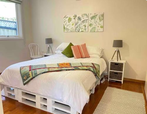 a bedroom with a white bed with two lamps and a window at Gippsland Getaway in Moe