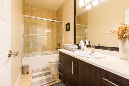 Beach Breeze White Rock في وايت روك: حمام مع حوض ومرحاض ومرآة