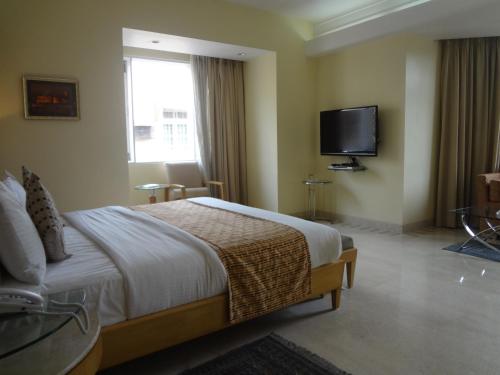 a bedroom with a bed and a flat screen tv at Ascot Hotel in Mumbai