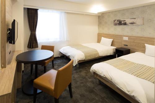 大阪的住宿－大阪心齋橋NEST酒店，酒店客房设有两张床和一张桌子。