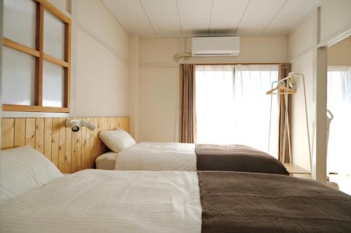 een hotelkamer met twee bedden en een raam bij 駅近商業施設近くで便利 静かで心ほぐれる滞在が叶う宿neuk Hill 定員5名 無料駐車場有 in Fukuroi