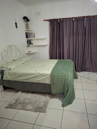 a bedroom with a bed with a green blanket at Canberra on Greenwood in Cape Town