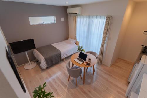 a small room with a bed and a table with a laptop at Sion NAGOYA in Nagoya