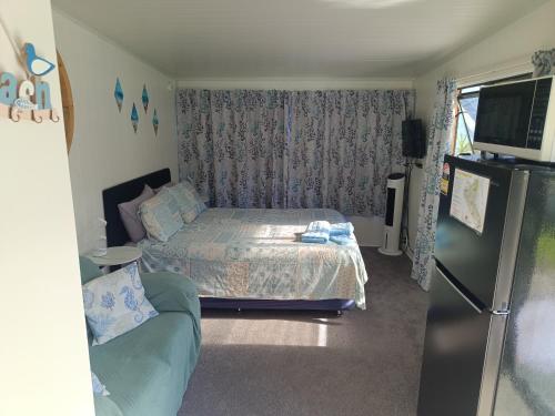 a small bedroom with a bed and a refrigerator at Riverview Studio in Te Puru