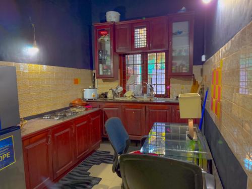 Sanhinda Rooms Nugegoda في نوغيغودا: مطبخ مع دواليب حمراء وطاولة زجاجية