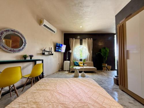 a living room with a large bed and yellow chairs at Departamento Belembi merida in Mérida