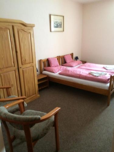 a bedroom with two beds with pink sheets and a chair at Penzión Duna & soľná jaskyňa in Komárno