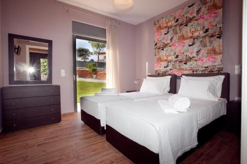 two beds in a bedroom with a wall with flowers at Ameadros Resort in Mantzavináta