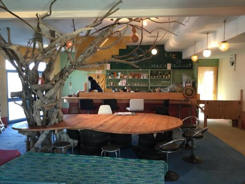 a restaurant with a wooden table and a tree at Guest House & Cafe Ohana in Imabari