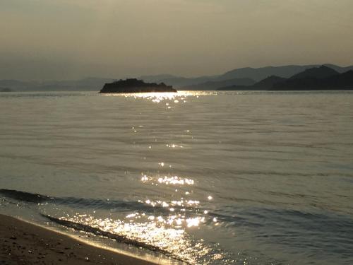 a beach with the sun reflecting off the water at Guest House & Cafe Ohana in Imabari