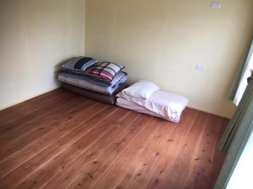 a small room with a bed and a wooden floor at Guest House & Cafe Ohana in Imabari